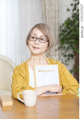 リビングでエンディングノートを書くシニア女性 リビングでエンディングノートを書くシニア女性 133125527