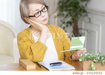 リビングでエンディングノート,通帳を見るシニア女性 133125552