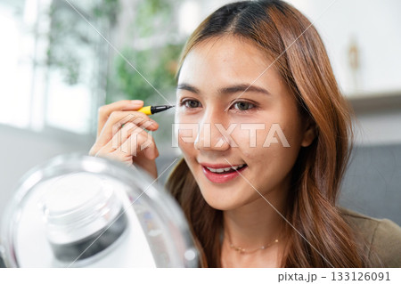 Beauty Routine. Young woman applying eyeliner while looking in mirror. 133126091