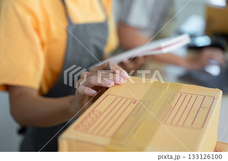 Small Business Operations. Employee preparing packages for shipment in a retail workspace. 133126100
