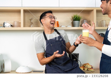 Couple Sharing a Drink. Men laughing and enjoying beverages in a modern kitchen. 133126208