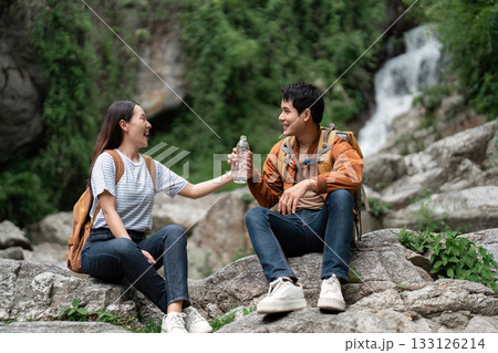 Outdoor Adventure. Young hikers sharing water during a mountain trek. 133126214
