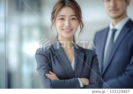 自信のある表情で腕組みをするスーツ姿の笑顔の若い女性と男性ビジネスマン 133129887