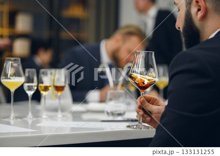Sommelier looking at color of drink during alcohol beverages training. Training of restaurant staff, studying alcohol list. 133131255