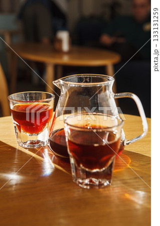 Enjoying Alternative Brewed Coffee in Transparent Cups on Wooden Table at Sunlit Cafe 133131259