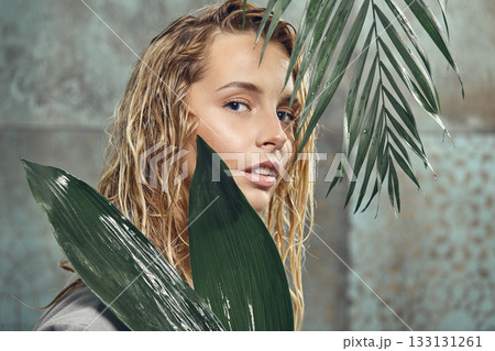 young beauty woman with a perfect skin holds tropical petals near face, close up. 133131261