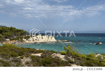 View of Kavourotrypes beach, official nudist beach, Summer sunny day blue sky sea stones, people sunbathing. Sithonia peninsula, Greece View of Kavourotrypes beach, official nudist beach, Summer sunny day blue sky sea stones, people sunbathing. Sithonia peninsula, Greece 133131666