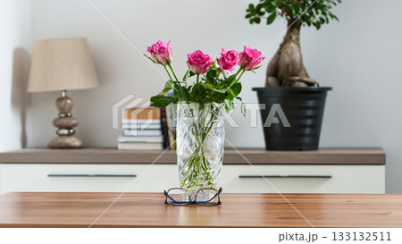 prescription glasses on a table against the background of a vase of flowers in a home setting 133132511