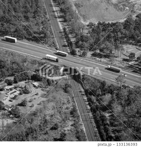 Trucks crossing over a road and railway in a wooded area during daytime Trucks crossing over a road and railway in a wooded area during daytime 133136393