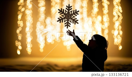 Silhouetted Child Reaching Up Touching Snowflake Decoration With Wonder and Amazement Expression Visible 133136721