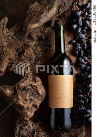 Bottle of red wine with blue grapes and old weathered snags. 133136760