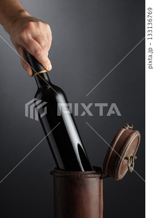 Sommelier places a bottle of red wine in an old wooden box. 133136769