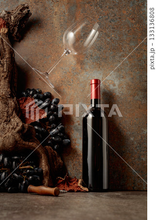Bottle of red wine with blue grapes on a rusty background. 133136808
