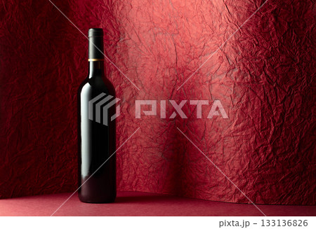 Bottle of red wine on a red background. 133136826