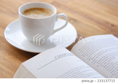 ページを開いた本(洋書)とコーヒーの入ったコーヒーカップで、コーヒーを飲みながら読書を楽しむイメージ ページを開いた本(洋書)とコーヒーの入ったコーヒーカップで、コーヒーを飲みながら読書を楽しむイメージ 133137715