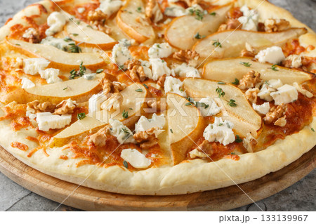 Delicious pizza with pears, gorgonzola cheese, walnuts and herbs closeup on the wooden board. Horizontal 133139967