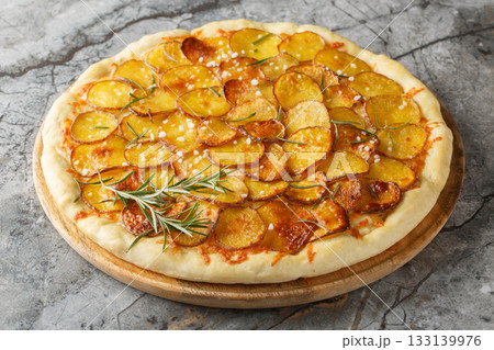 Vegetarian Potato rosemary pizza sprinkled with coarse salt and baked until crispy close-up on a wooden board. Horizontal 133139976