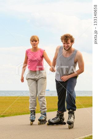 Man encourage woman to do rollerblading Man encourage woman to do rollerblading 133140658