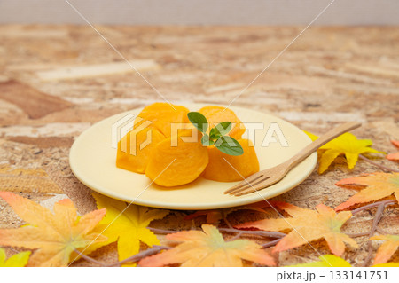 皿に盛り付けられた秋の味覚の柿　カットした柿とミントの葉とフォーク 133141751