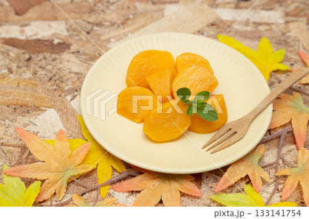 皿に盛り付けられた秋の味覚の柿　カットした柿とミントの葉とフォーク 133141754