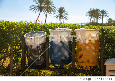 Three colorful mesh trash cans in tropical park Three colorful mesh trash cans in tropical park 133142234