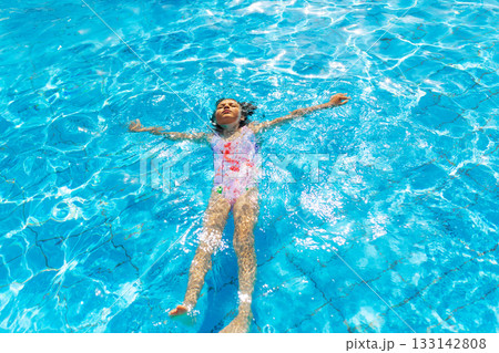 Portrait of resting 7 years old girl floating on his back in swimming pool on sunny day 133142808