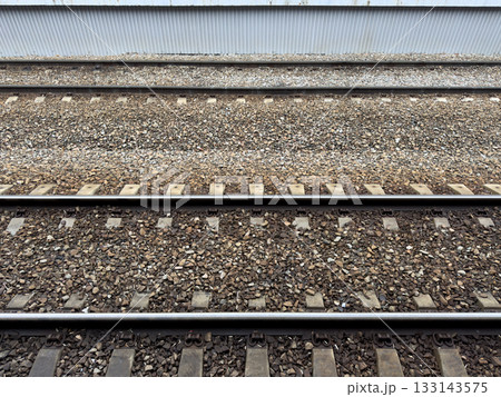Railroad tracks covered with crushed stone. View from the platform onto the tracks for arriving trains at the station. Concept of railroads as means of transporting people and goods 133143575