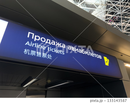 Ticket counter at airport. The Airplane Tickets sign in Russian, English, and Chinese for multicultural navigation in modern airport. Buying ticket in unknown city to travel the world Ticket counter at airport. The Airplane Tickets sign in Russian, English, and Chinese for multicultural navigation in modern airport. Buying ticket in unknown city to travel the world 133143587