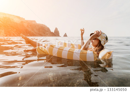 Woman Float Sea Relaxing on inflatable ring in sea against rocky cliff. Woman Float Sea Relaxing on inflatable ring in sea against rocky cliff. 133145050