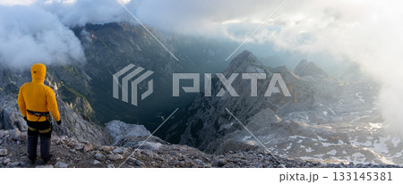 Hiker on a mountain summit enjoying beautiful alpine scene during sunrise, Slovenia Hiker on a mountain summit enjoying beautiful alpine scene during sunrise, Slovenia 133145381