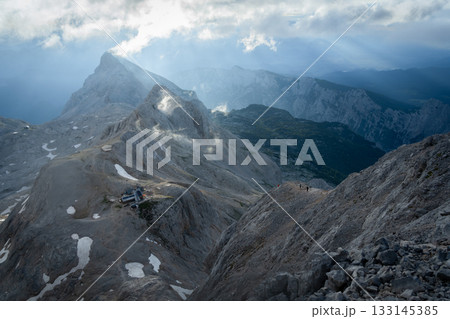 Alpine landscape with hikers and mountain hut lit by early morning soft light, Slovenia Alpine landscape with hikers and mountain hut lit by early morning soft light, Slovenia 133145385