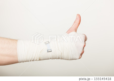 Man with bandaged hand showing thumb up. Man with bandaged hand showing thumb up. 133145418