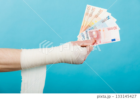 Male bandaged hand with money. Male bandaged hand with money. 133145427