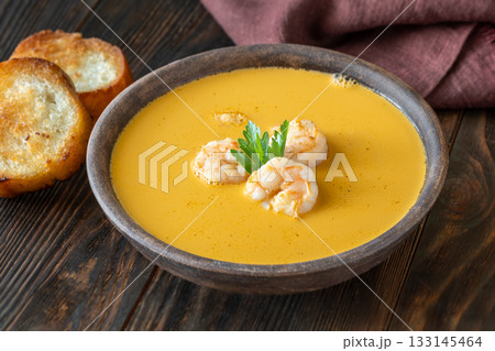 Rustic shrimp bisque with toasted baguette slices beside clay bowl Rustic shrimp bisque with toasted baguette slices beside clay bowl 133145464