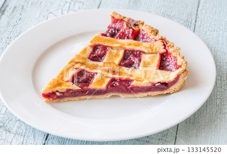 Wedge of freshly baked lattice-top cherry pie served on white plate 133145520