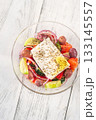 Fresh traditional Greek salad topped with thick feta slice served in glass bowl 133145557