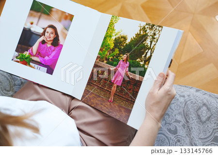 woman is holding and flipping through a photo book with a pregnancy photo shoot 133145766