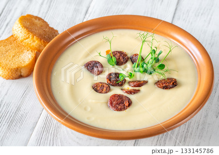 Terracotta bowl of creamy cauliflower soup paired with toasted baguette on bright wooden surface Terracotta bowl of creamy cauliflower soup paired with toasted baguette on bright wooden surface 133145786