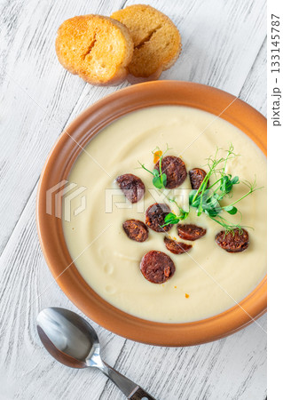 Terracotta bowl of creamy cauliflower soup paired with toasted baguette on bright wooden surface Terracotta bowl of creamy cauliflower soup paired with toasted baguette on bright wooden surface 133145787