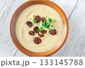 Creamy cauliflower soup with spicy chorizo served warmly in terracotta bowl on white table 133145788
