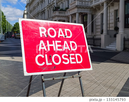Road Ahead Closed sign on tripod in city street, traffic detour and roadworks warning 133145793