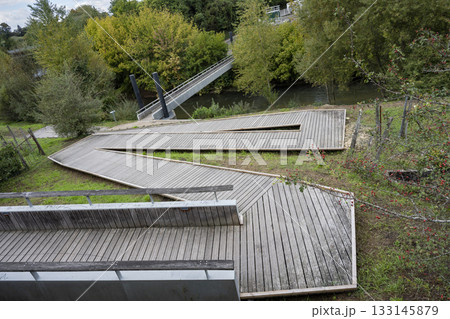 Walkway near river in Mont de Marsan surrounded by greenery and bridges 133145879