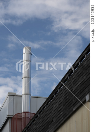 Metal chimney against blue sky with scattered clouds in an industrial area 133145953