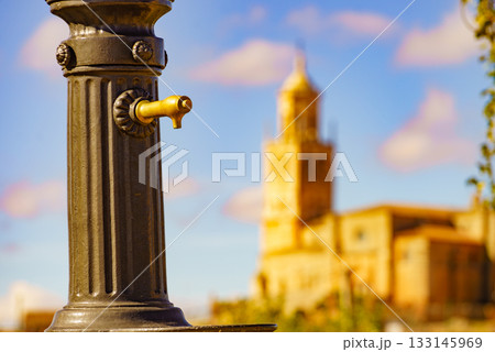 Old hydrant and church in town Santa Maria del Campo, Spain. Old hydrant and church in town Santa Maria del Campo, Spain. 133145969