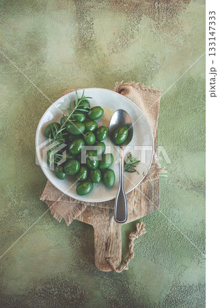 Chalkidiki olives, classic Greek green olive, on a plate, with a spoon, top view, no people, Chalkidiki olives, classic Greek green olive, on a plate, with a spoon, top view, no people, 133147333