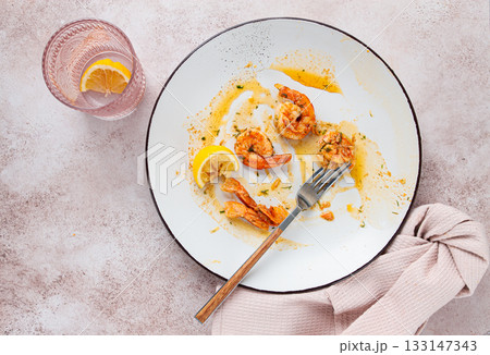 the remains of fried shrimp in oil with spices, on a white plate, with a fork, there are no people, 133147343