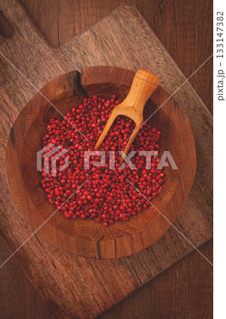 Bright red peppercorns, in a wooden bowl, with a small wooden tray, 133147382