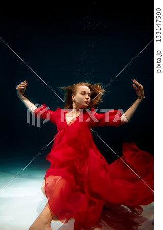 caucasian choreographer demonstrating underwater in red dress 133147590