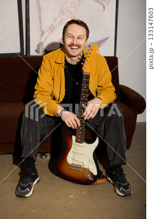 Relaxed man playing electric guitar in vibrant light setting 133147603