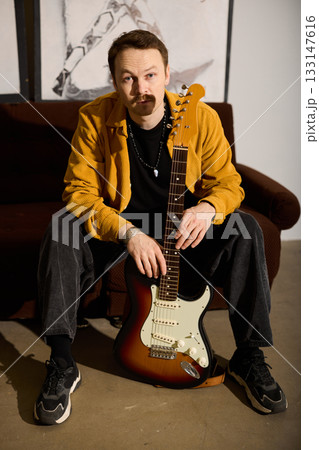 Guitarist ready pose, Man prepares guitar with confidence Guitarist ready pose, Man prepares guitar with confidence 133147616